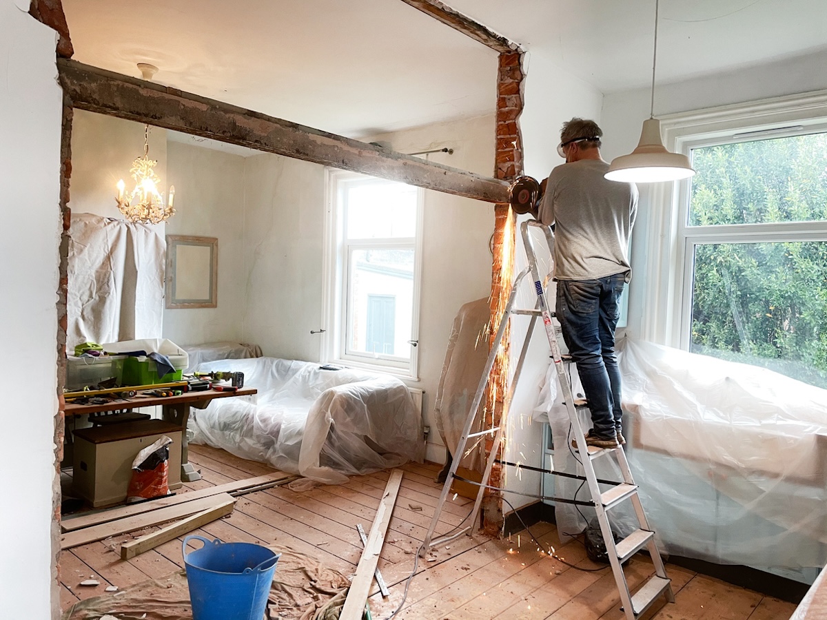 Personne qui démolit un mur avec du plastique sur les meubles