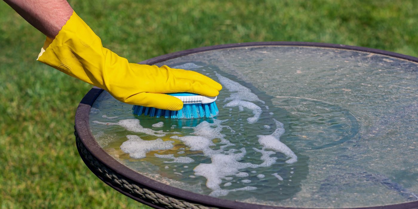 Personne nettoyant les meubles extérieurs avec de l'eau savonneuse et une brosse