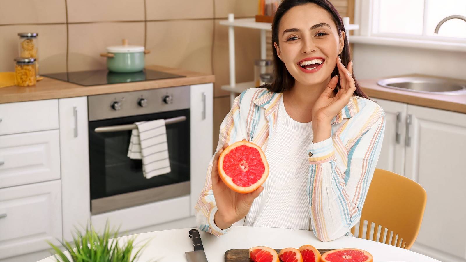 Femme souriante tenant un pamplemousse